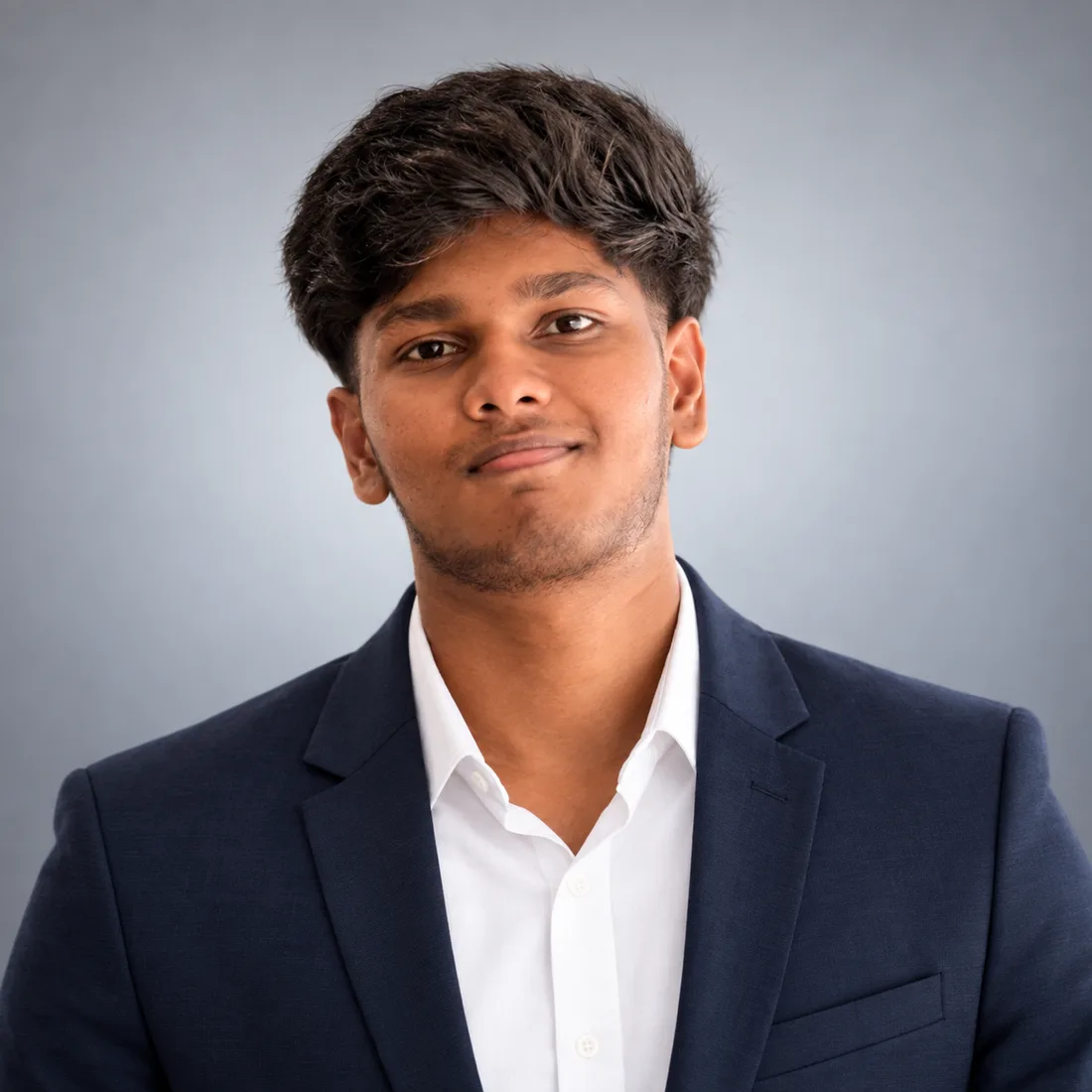 Alex Shanjay, video editor and graphic designer, in a navy blazer and white shirt